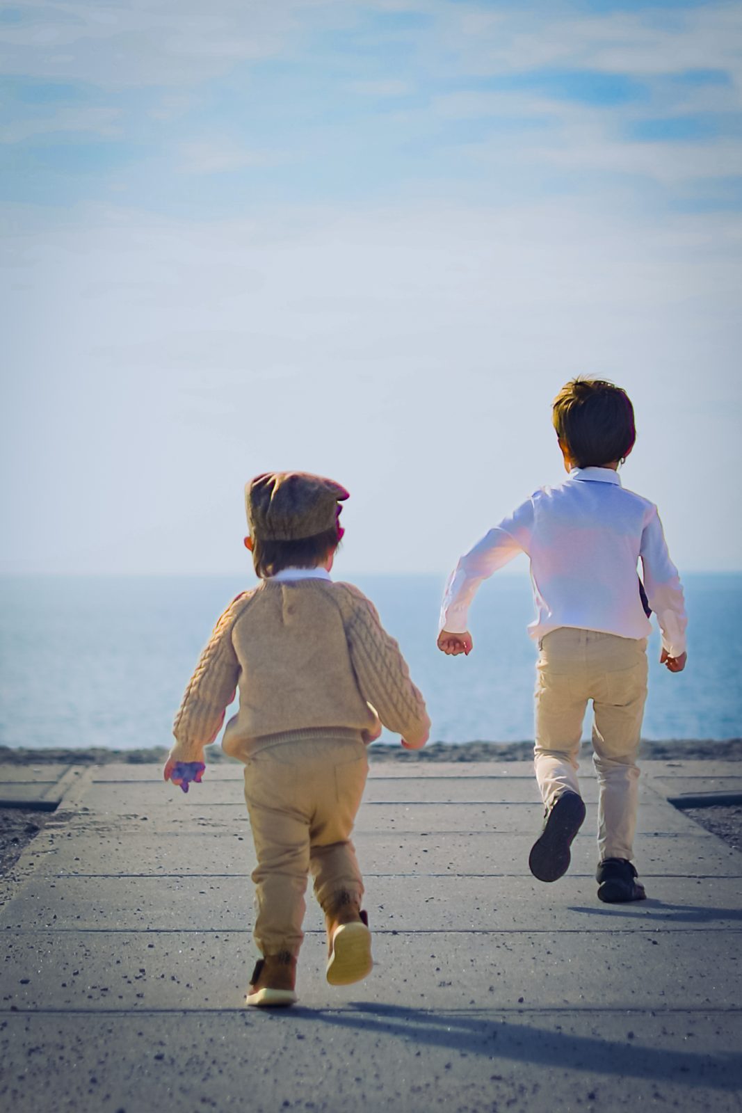 Two boys running toward the sea