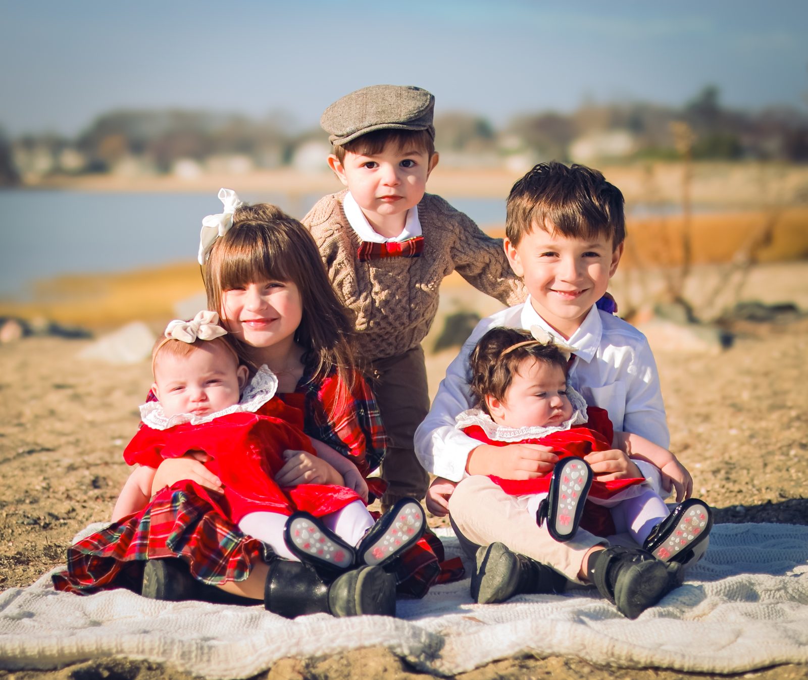Five siblings on a beach blanket in holiday outfits
