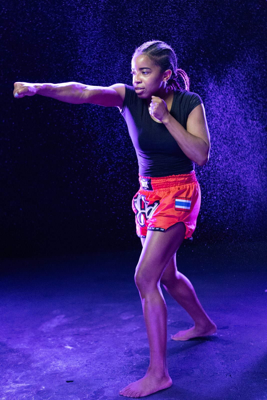 Muay Thai fighter throwing a jab in purple mist