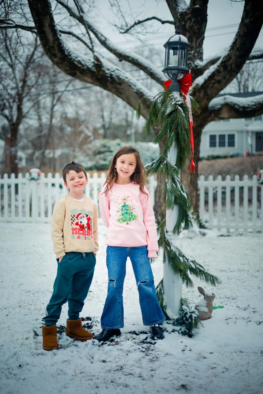 Brother and sister in the snow by a decorated lamp post